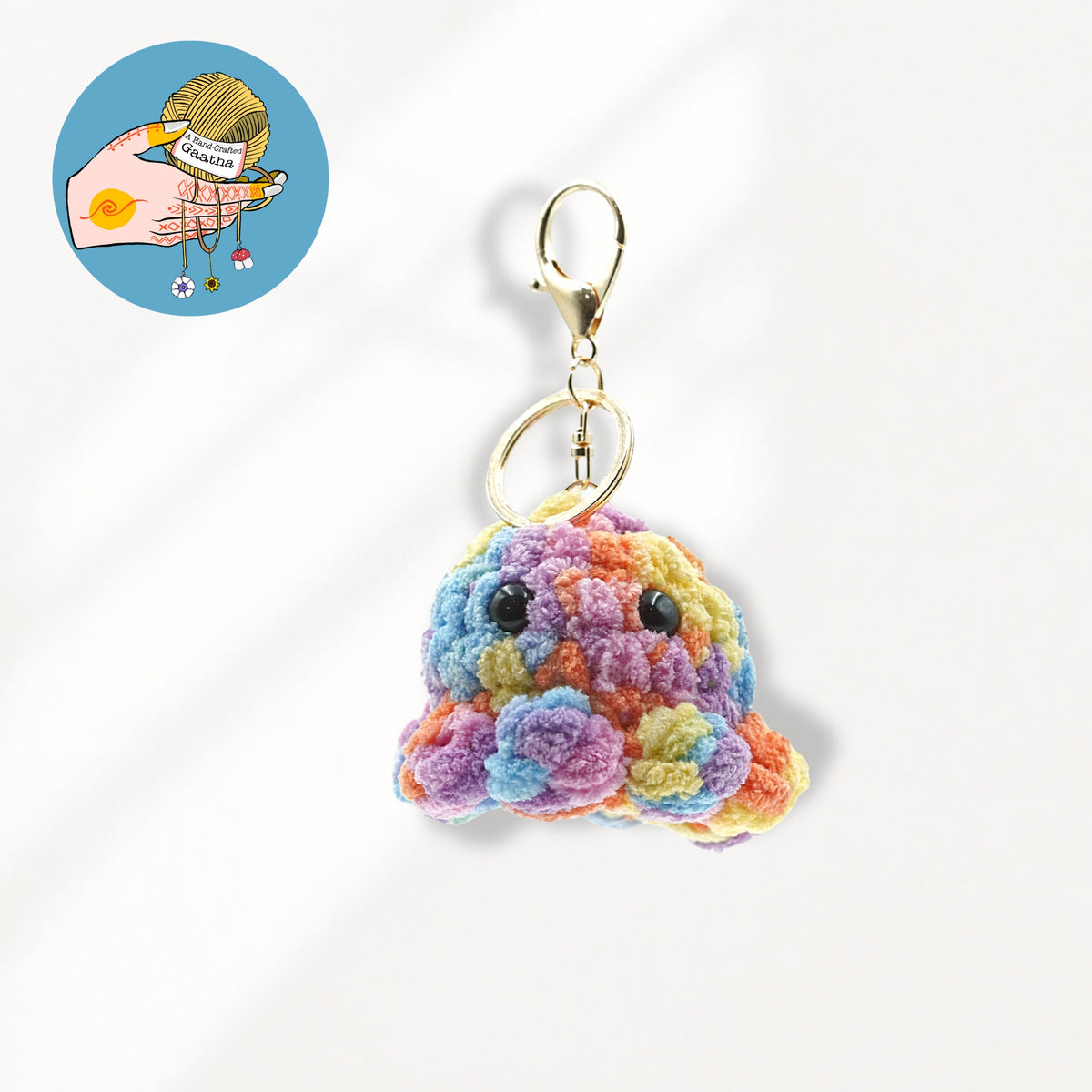 A colorful crocheted monster keychain charm with a gold lobster clasp.